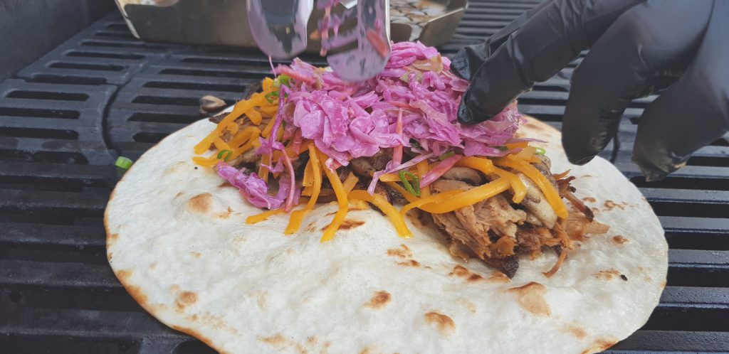Der Pulled Pork Burrito wird mit den Zutaten belegt.